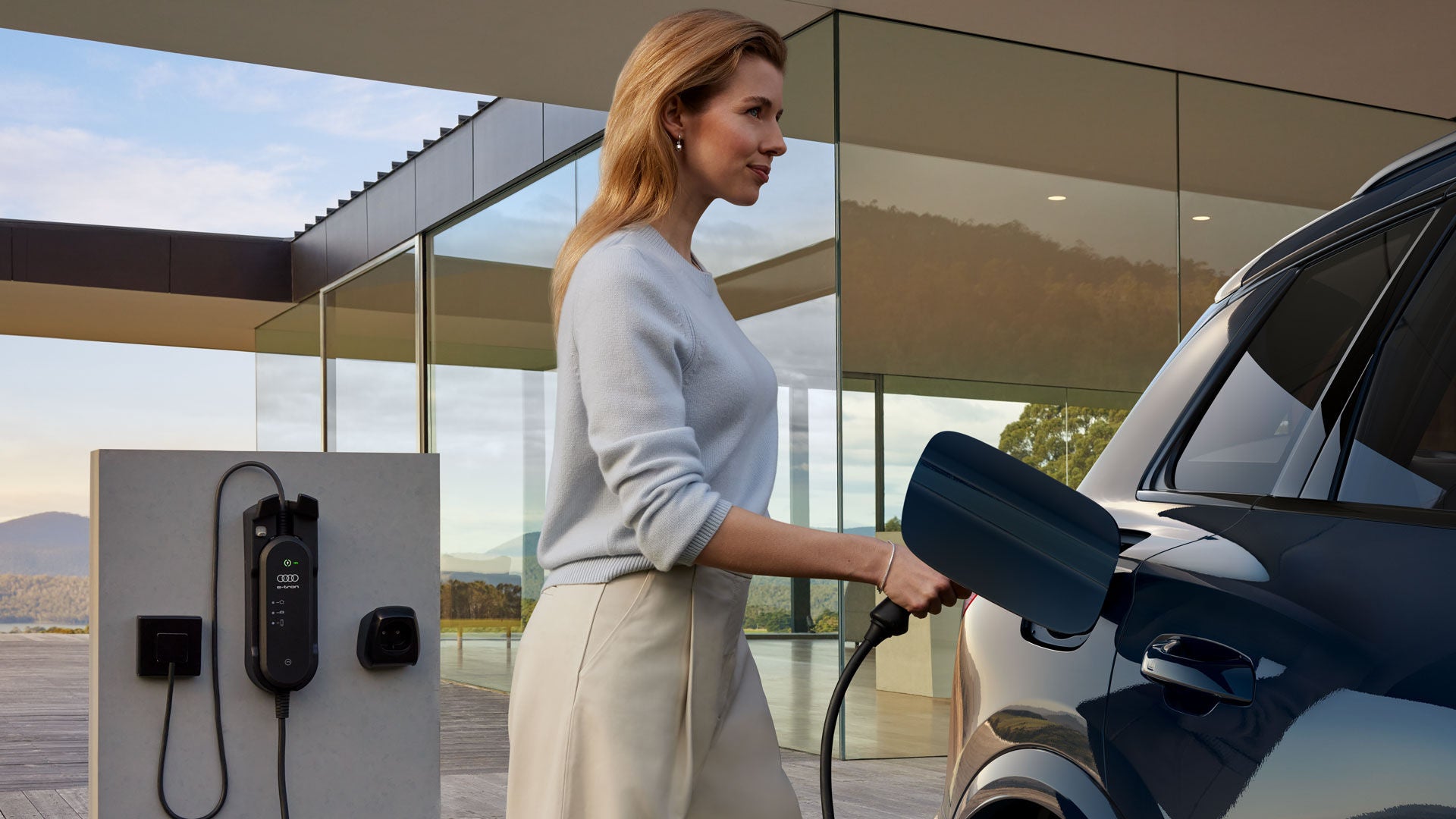 En person står och laddar en Q6 e-tron.