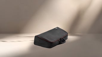 Sac de coffre Audi noir avec fermeture à glissière et poignée de transport, photographié en fond perdu sur un fond clair et neutre, avec des effets d'ombre et de lumière doux.