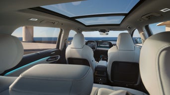 Blick vom Rücksitz auf den Innenraum eines Audi mit Panoramadach und digitalem Cockpit bei Tageslicht.