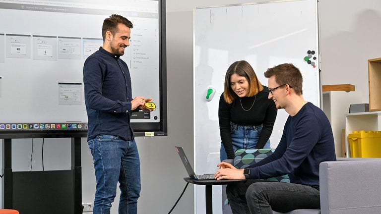 Lisa, Product Designer SDC, looks at a laptop with a colleague