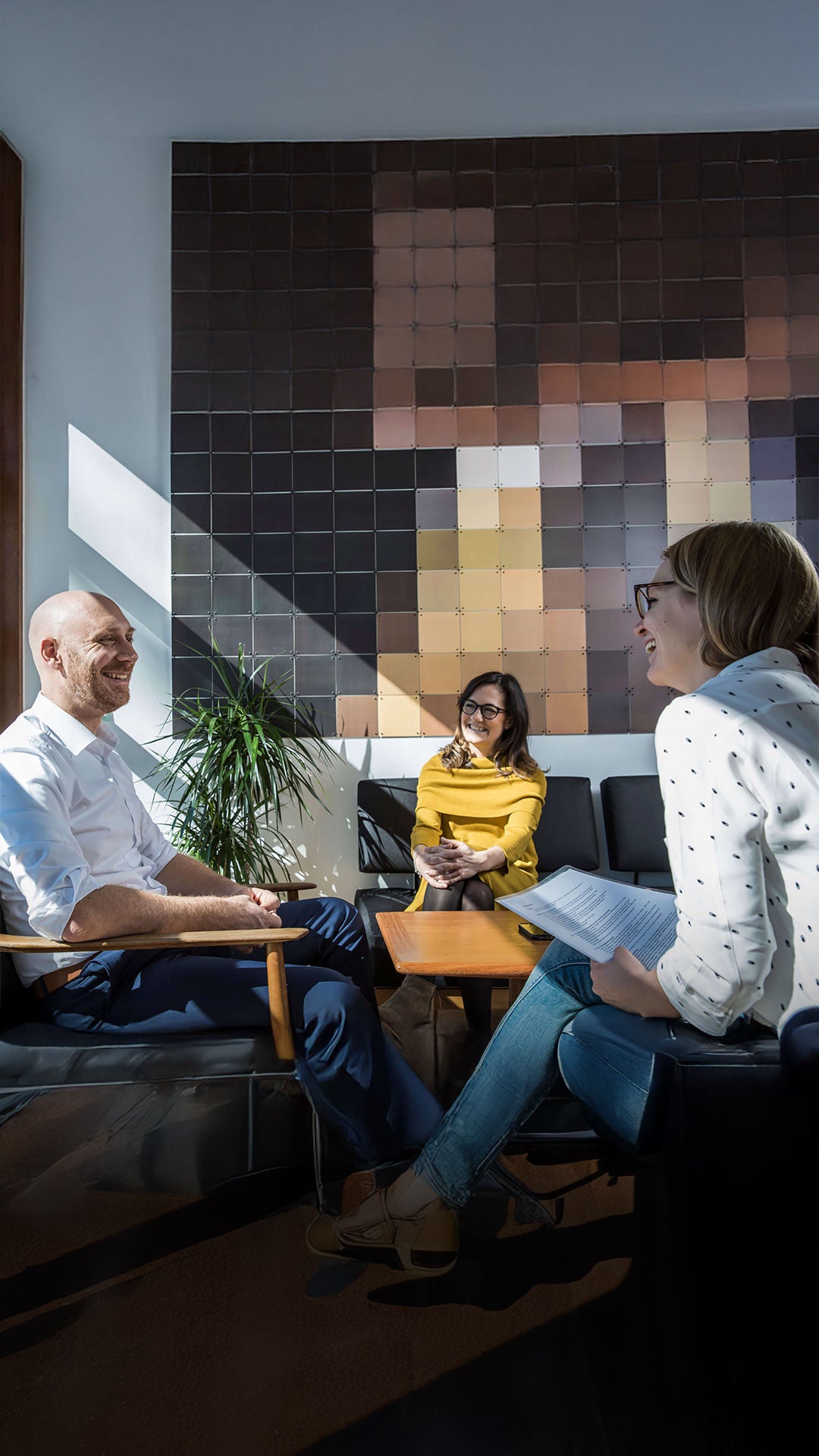 3 Personen sitzen um einen Tisch herum und sprechen miteinander