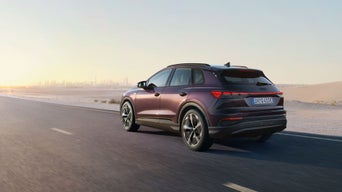 Ein lilaner Audi fährt auf einer Straße, daneben eine Wüstenlandschaft.