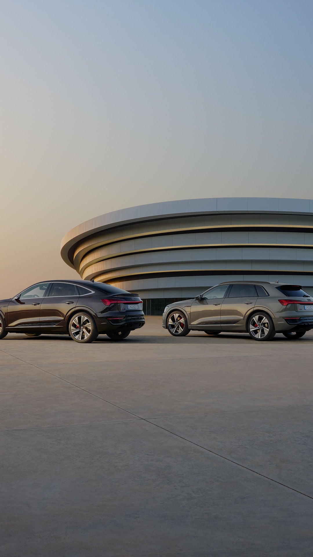 Two Audi SUV cars next to each other in front of a modern spectacular building