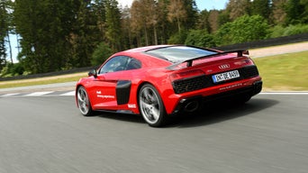 Red Audi R8 Coupé V10 performance quattro driving on a race track, rear view.
