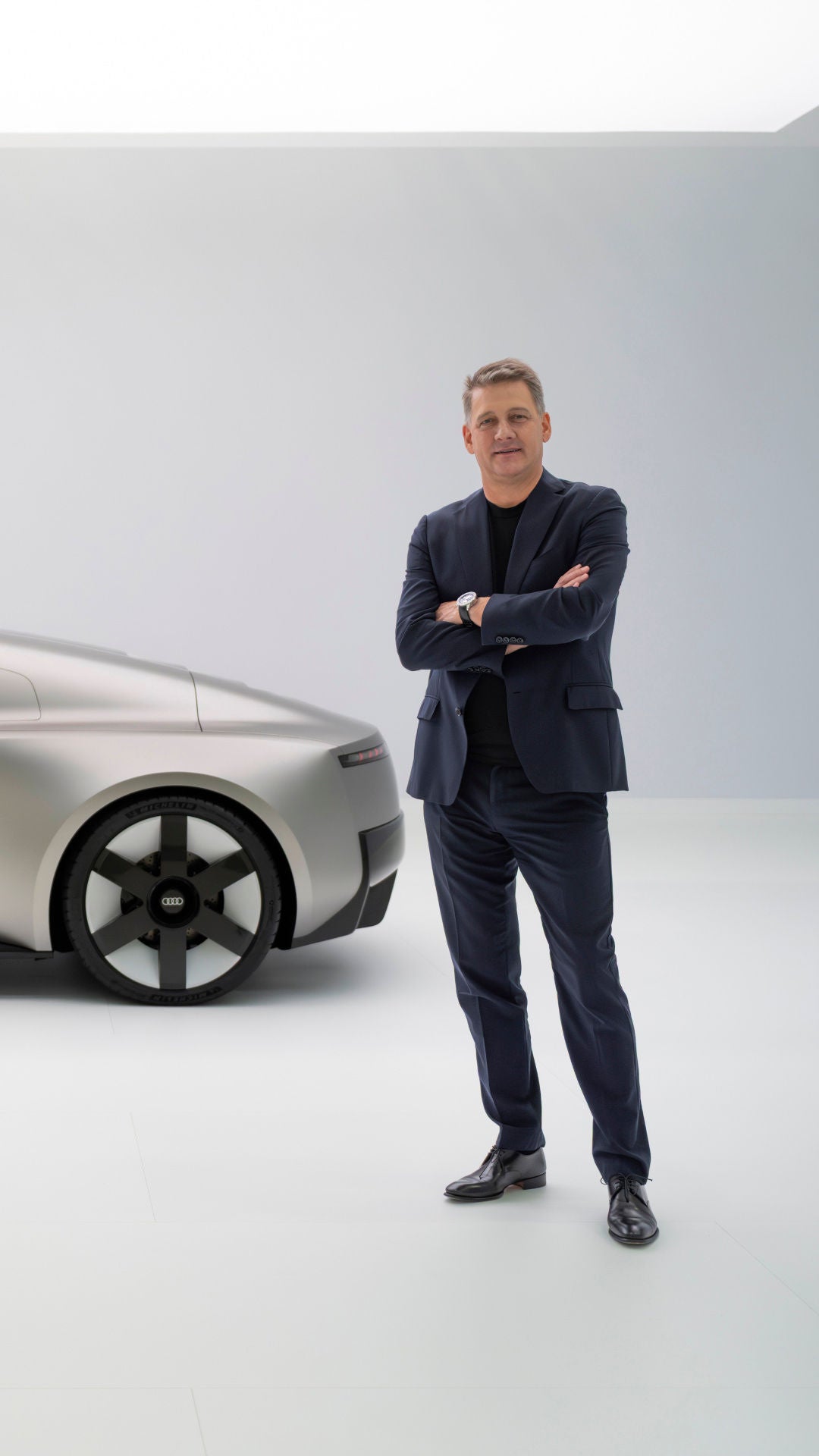 Audi CEO Gernot Döllner steht rechts vom Audi Concept C vor einer weißen Wand in einem hellen Studio