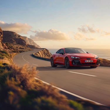 Red Audi e-tron GT quattro cruising on a curvy coastal road