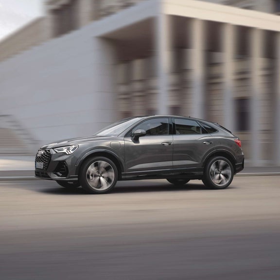 Side view of a dark grey Audi Q3 with a blurred background.