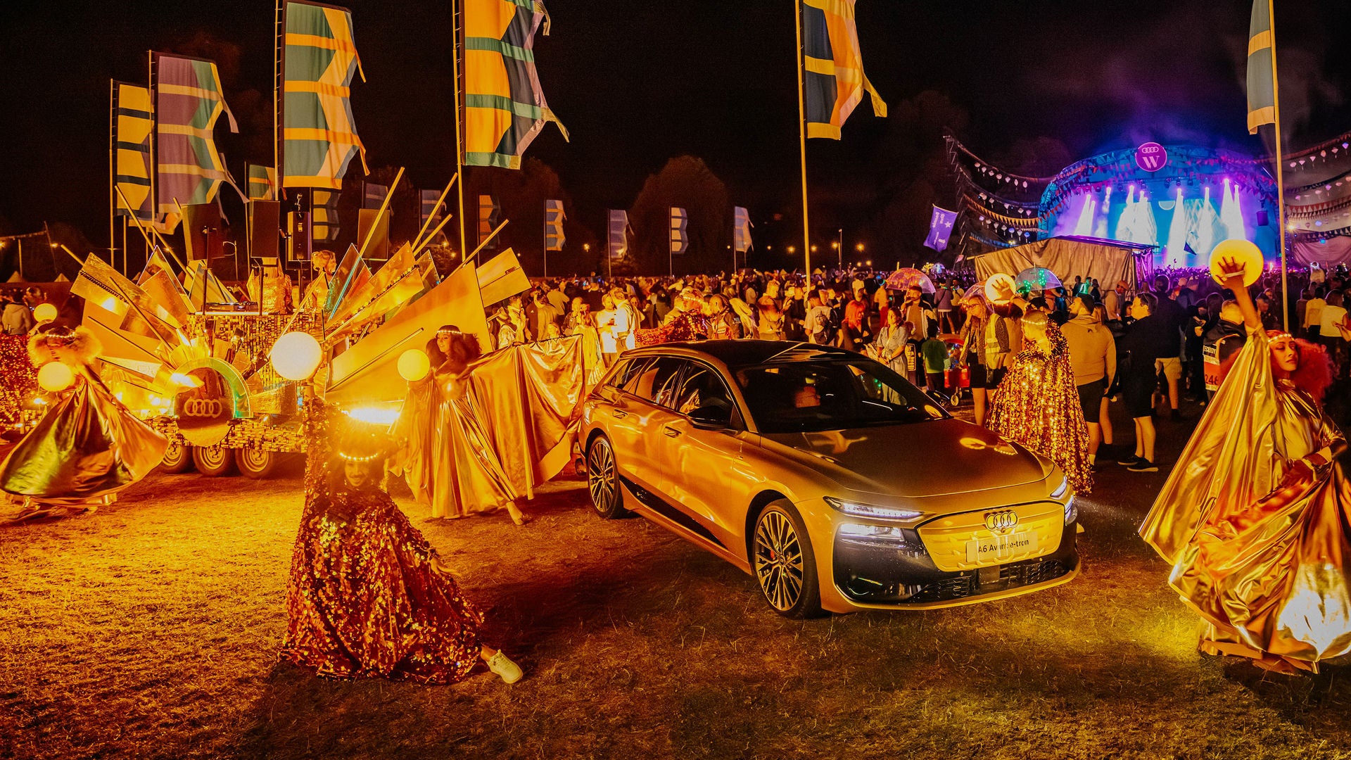 Drummers dressed up in front of an Audi car at a festival