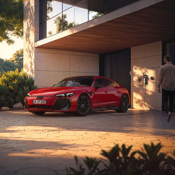 Audi e‑tron GT quattro in ricarica davanti a una casa
