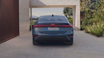 The back of a light blue Audi car with red details while parked next to a house