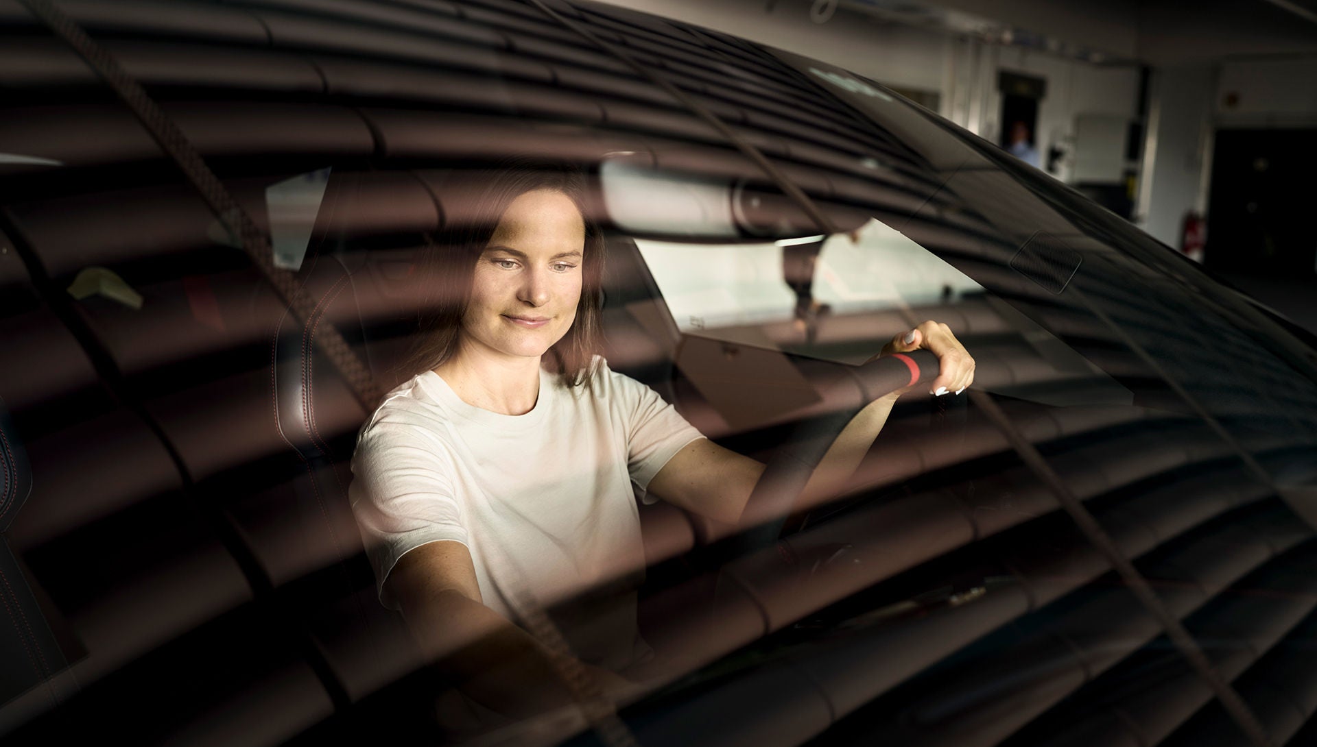 Melanie Schillinger is sitting in an Audi, looking down with one hand on the steering wheel