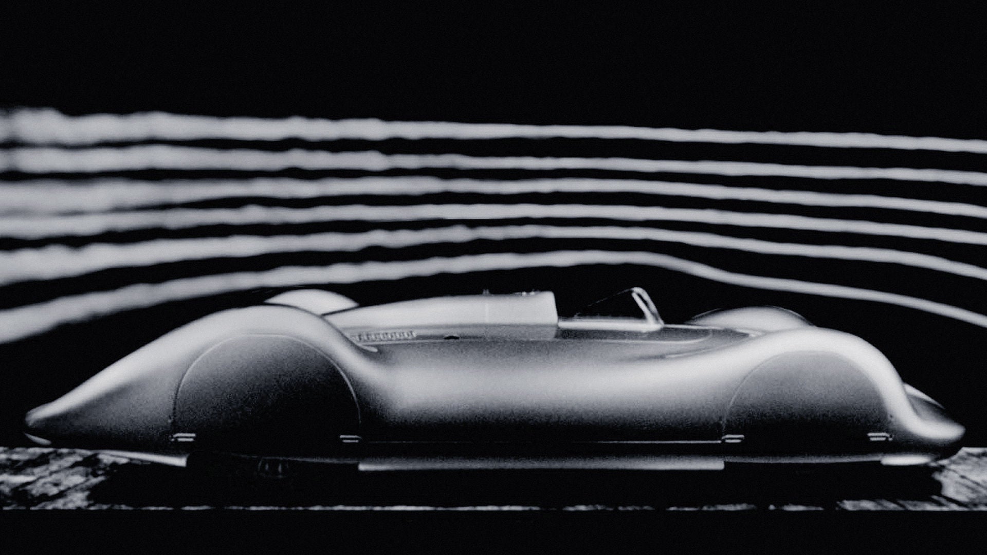 Side view of a fully clad, historic Audi racing car against a dark background. Streamlines are indicated above the vehicle.