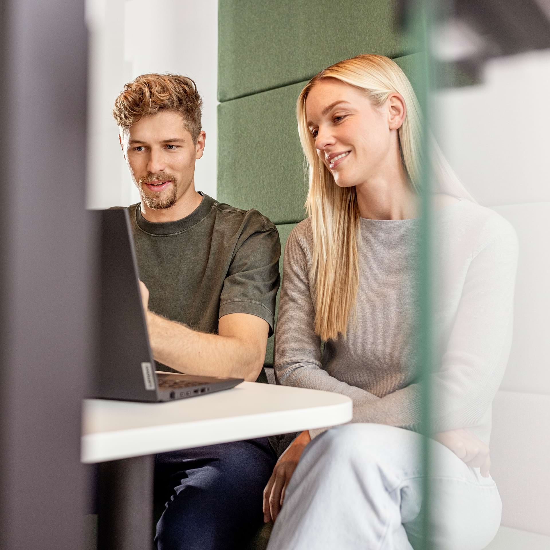 Junge, blonde Frau hält ein Pad in der Hand und lächelt in die Kamera