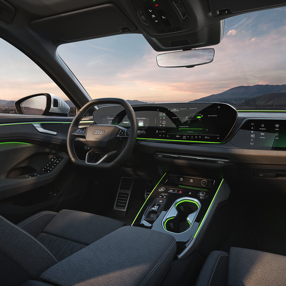 Audi interior showcasing a modern dashboard, green accents, and high-tech displays against a sunset landscape outside.