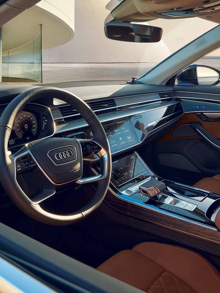Cockpitansicht des Audi A8 L mit hellbraunem Lederinterieur und digitalem Display auf Mittelkonsole.