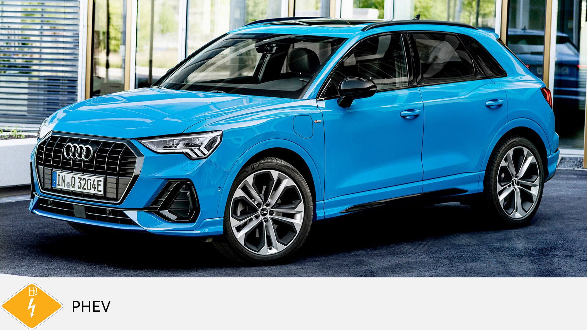 Blue Audi Q3 TFSI e standing in front of glass facade, shown slightly from the front. Yellow PHEV symbol with petrol pump below.