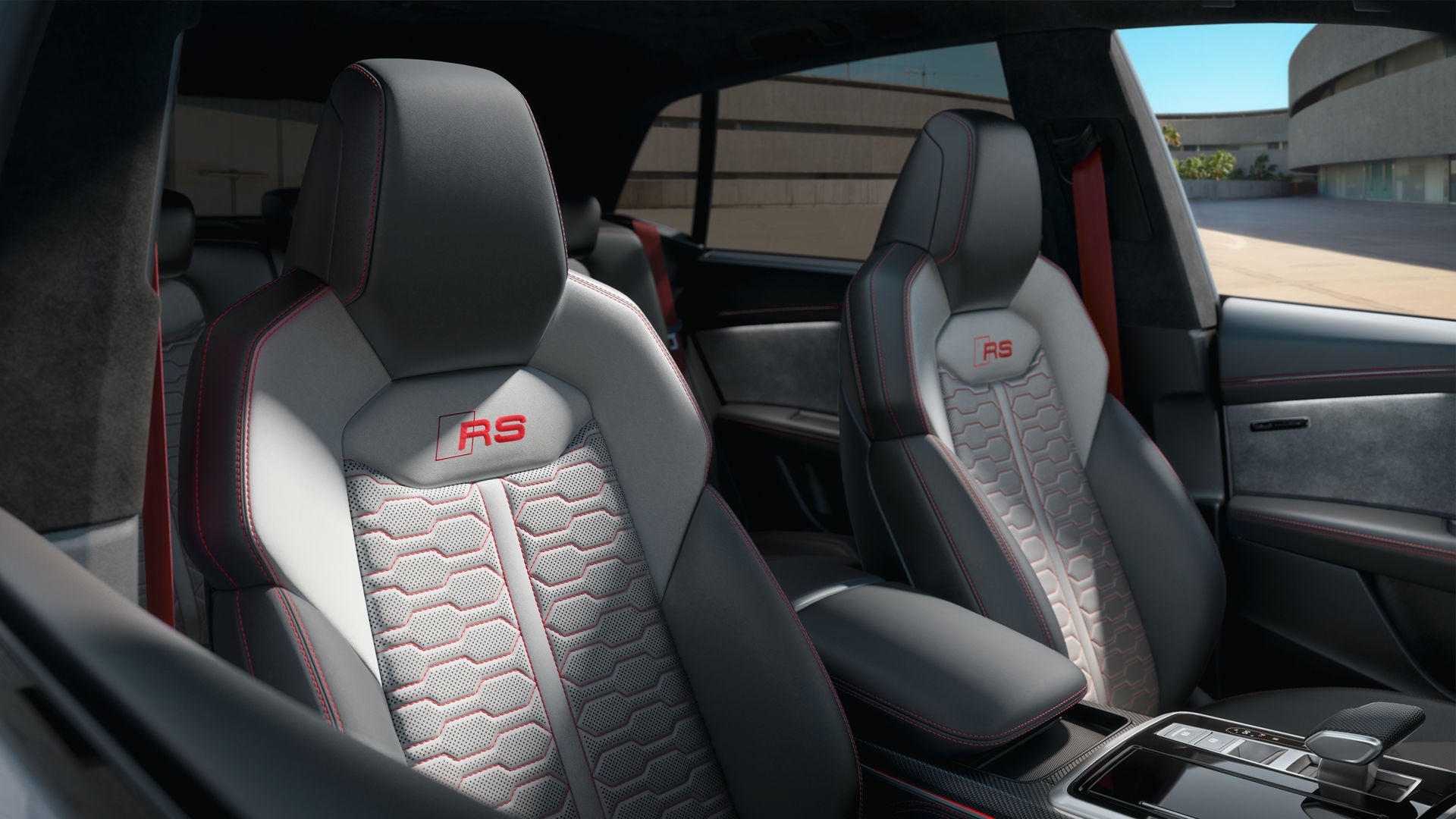 Een blik op de sportstoelen met Audi exclusieve Valcona lederen bekleding in Jet Grey/Silver, met contrasterende stiksels, veiligheidsgordels en een geborduurd RS-embleem op de rugleuningen en vloermatten in Crimson Red.