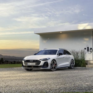 De A5 Avant e-hybrid staat geparkeerd voor een modern huis