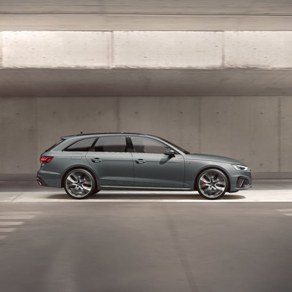 A modern grey car parked in a concrete parking garage.