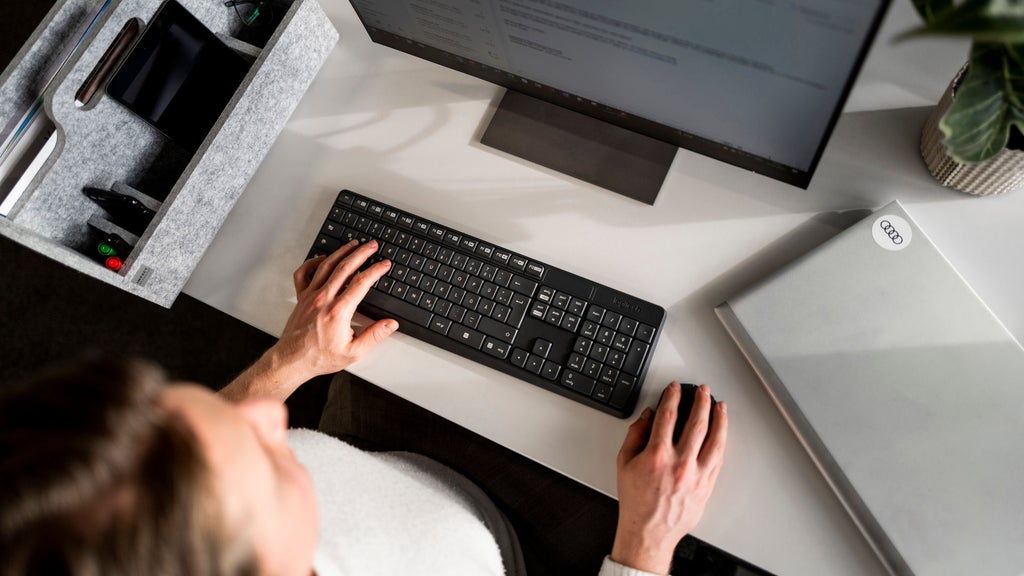 Eine Frau sitzt an einem Schreibtisch und arbeitet am Bildschirm