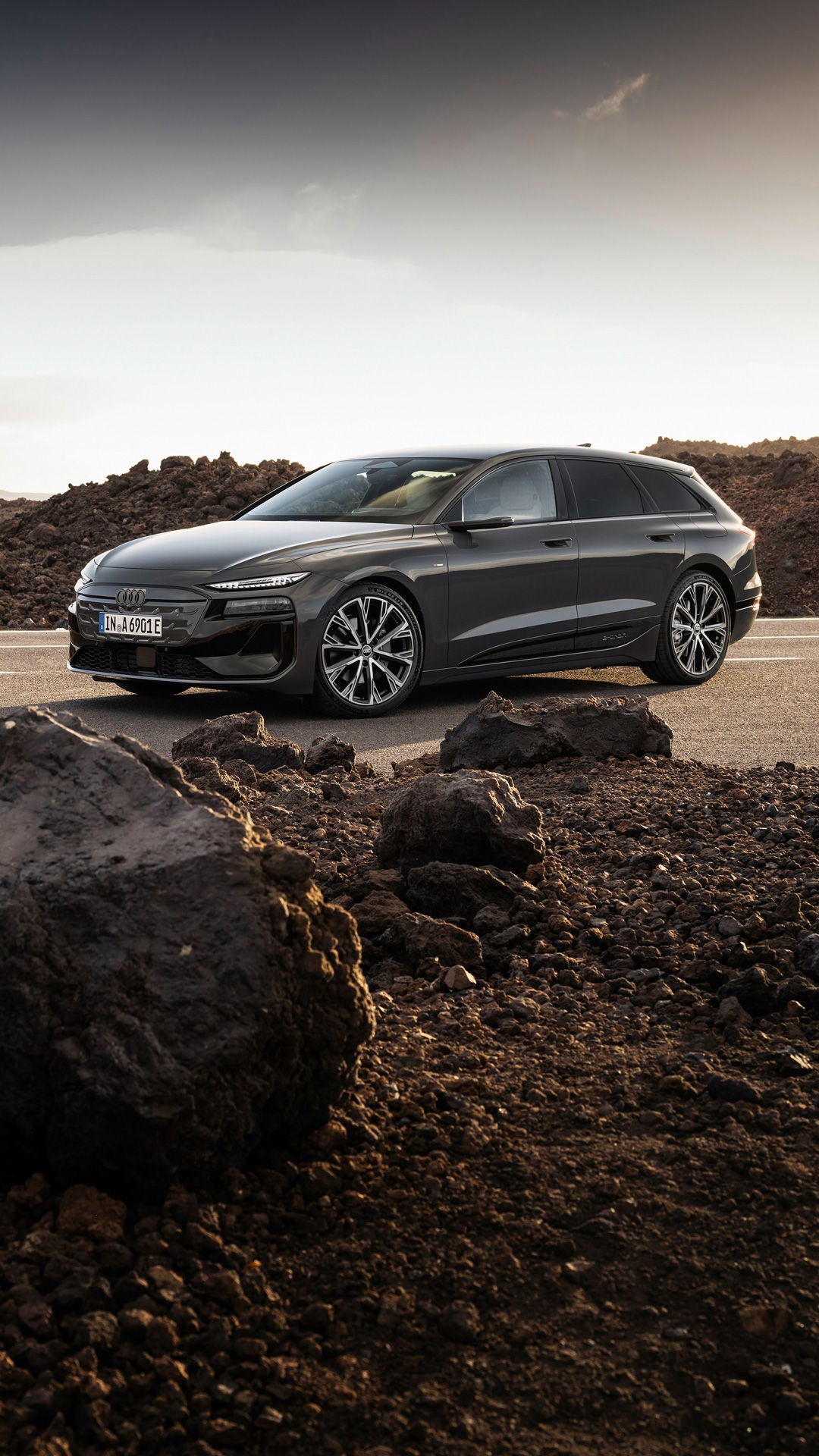 Audi A6 Avant e-tron performance stands on a road against a mountain backdrop. There are rocks and rubble next to the road.