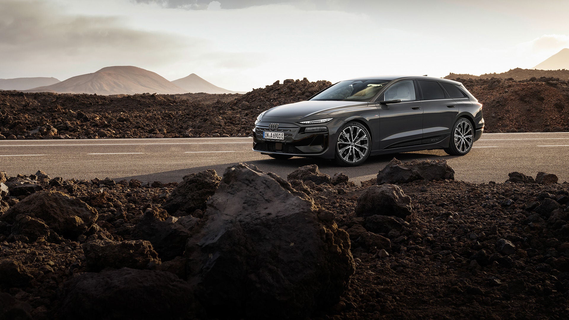 Audi A6 Avant e-tron performance steht auf einer Straße vor einer Bergkulisse. Neben der Straße liegen Felsen und Geröll.