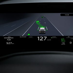 Nahaufnahme eines Displays im Fahrzeuginnenraum. Abgebildet ist die Silhouette eine Fahrzeugs in Geradeausfahrt. Vor der Front wird per grüner Grafik ein möglicher Spurwechsel dargestellt.