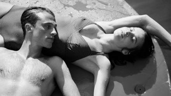 Meursault liegt am Strand mit dem Kopf auf dem Bauch seiner Freundin.