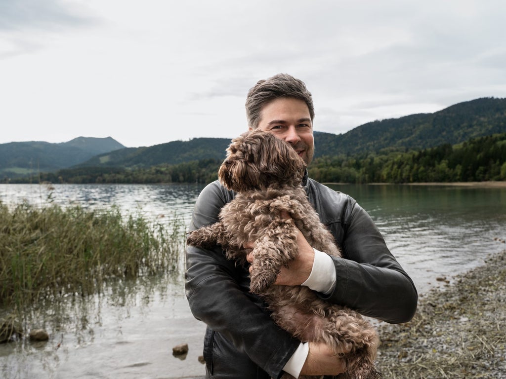Nils Wollny au bord du lac avec son chien dans les bras.
