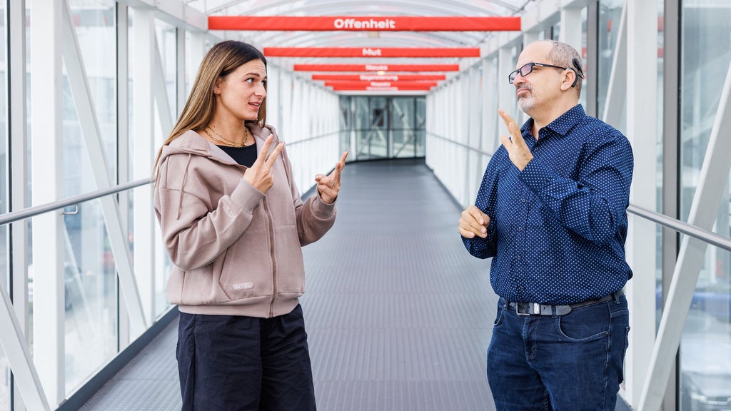 Vanessa is standing in a corridor next to her colleague Mathias, who is also deaf