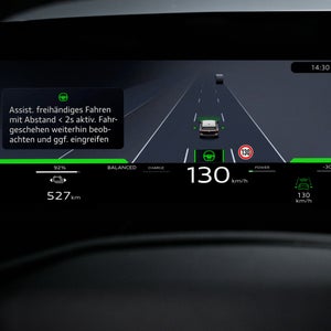 Nahaufnahme eines Displays im Fahrzeuginnenraum. Abgebildet ist die Silhouette eine Fahrzeugs in Geradeausfahrt. Links daneben ein Textkasten, der Informationen über das assistierte freihändige Fahren gibt.