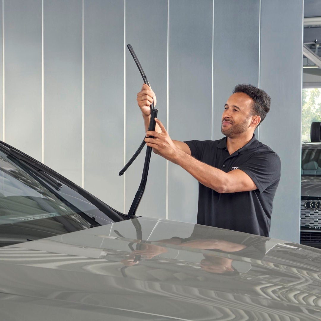 Un addetto all'officina monta delle nuove spazzole tergicristallo su un'auto Audi.