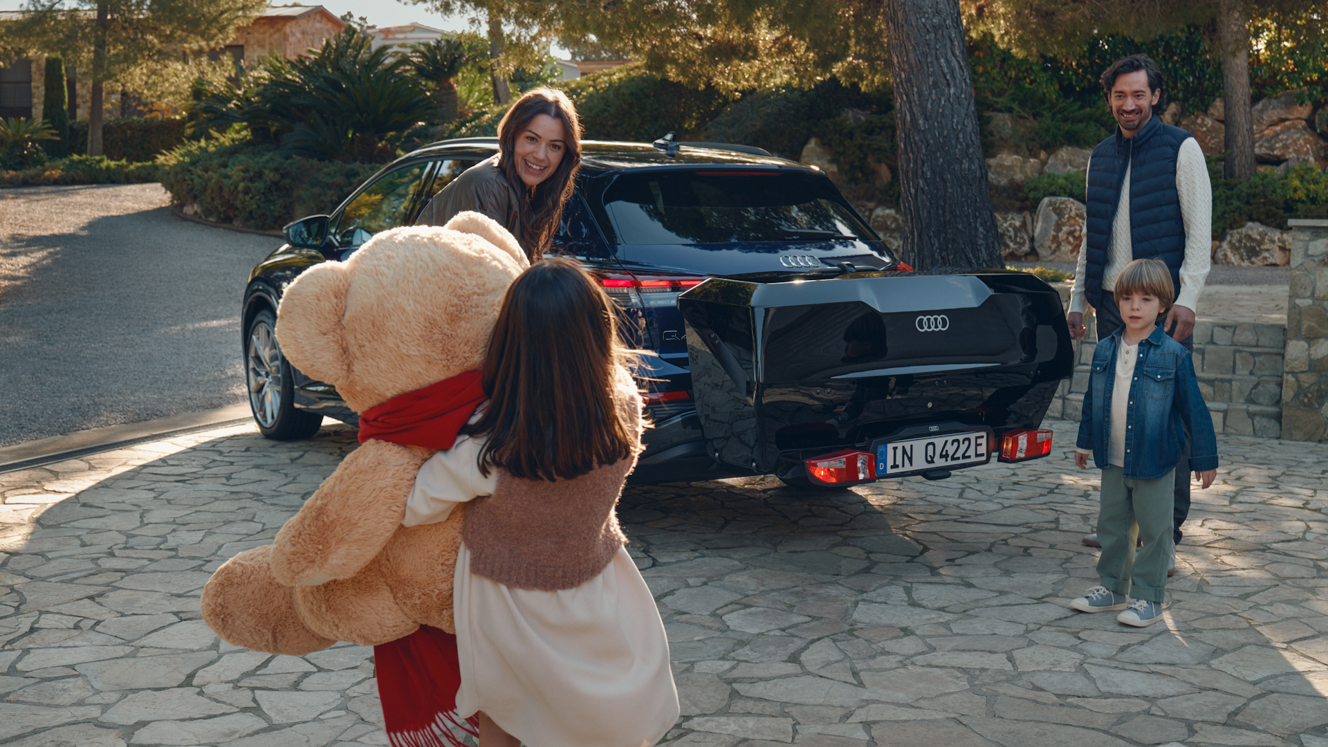 En Q4 e-tron med bagageboks på og en glad familie der er ved at pakke den