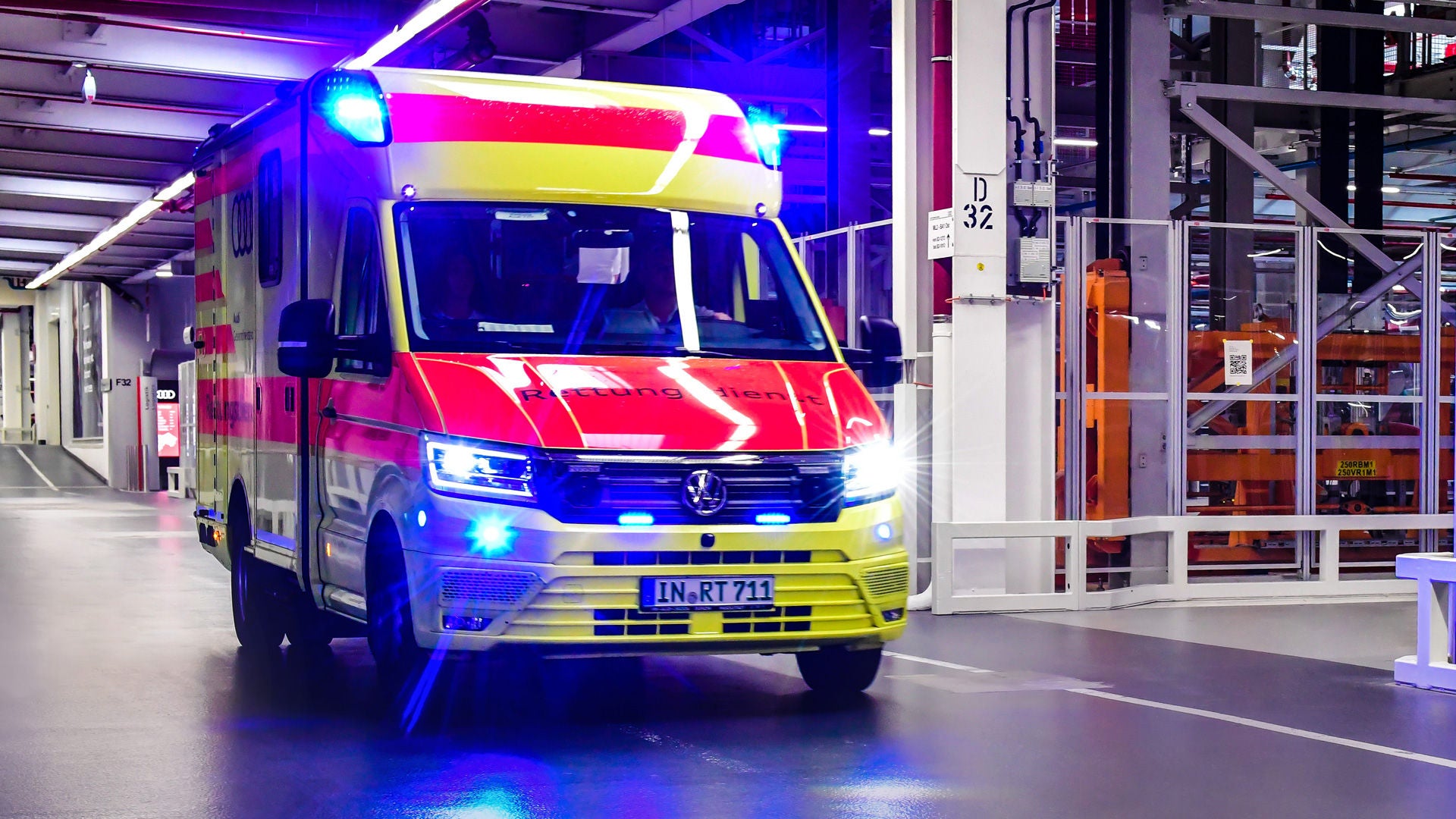 An ambulance with blue light and the inscription “Emergency Services” travels through the production line.
