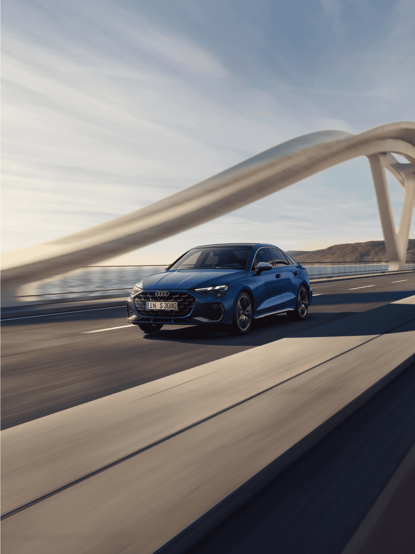 A blue car driving on a bridge with a unique arch structure under a clear sky.