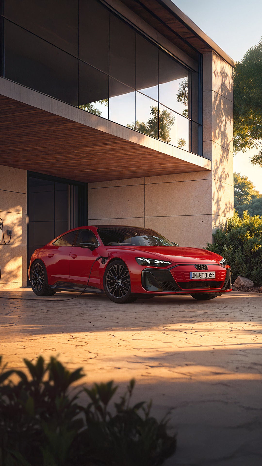 Audi e-tron GT quattro steht vor einer modernen Villa an der Ladesäule. Ein sportlich gekleideter Mann läuft auf das Auto zu.