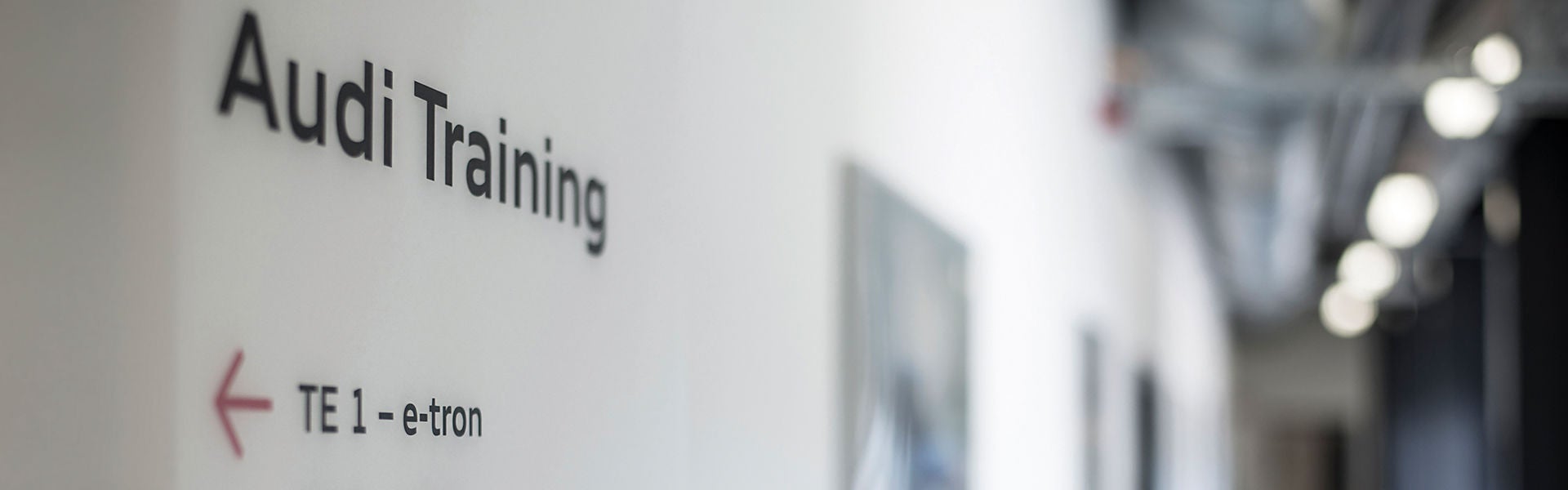 Ein Gang, an dessen Wand sich die Aufschrift Audi Training befindet, sowie ein Pfeil mit der Aufschrift "TE 1 e-tron".