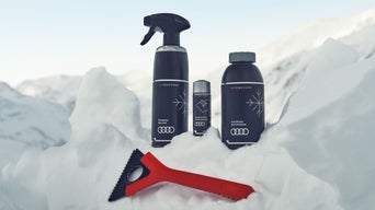 Audi Winterpflege-Set mit Enteiser, Glaspolitur, Frostschutz und Eiskratzer im Schnee.