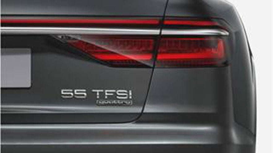 Heckansicht eines Autos mit Rückleuchte und Modellbezeichnung „55 TFSI quattro“ auf dunkler Lackierung.