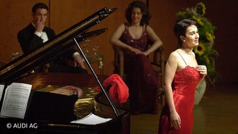 Frau im roten Kleid steht am Klavier