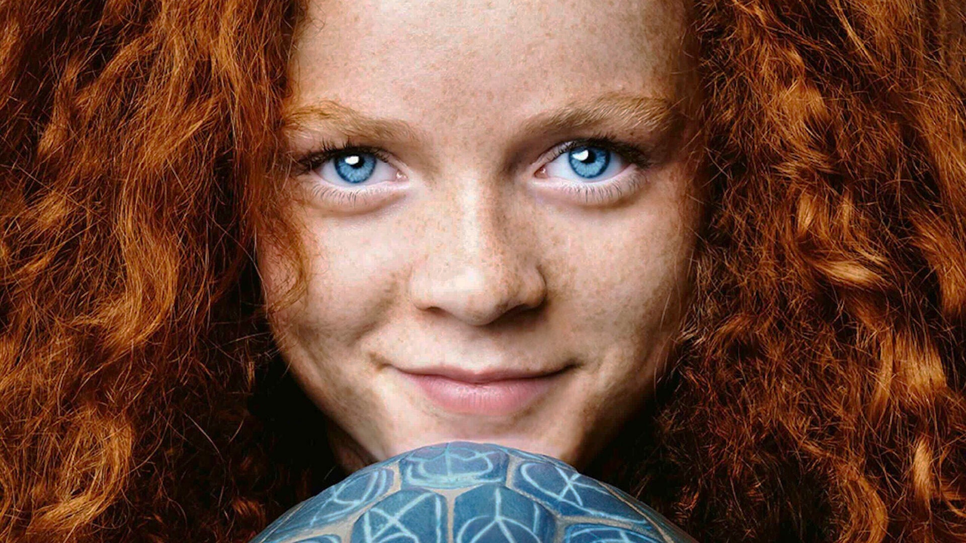 Großaufnahme von Momo mit ihren roten Locken und blauen Augen.