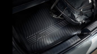 Schwarzer Gummischutz in einem Kofferraum mit A1 Logo. Darauf liegt eine schwarze Tasche.