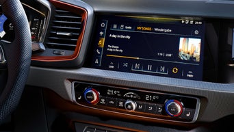 Infotainment-Display im Audi mit Musikwiedergabe „A day in the city“ und Bedienelementen für die Klimaanlage.