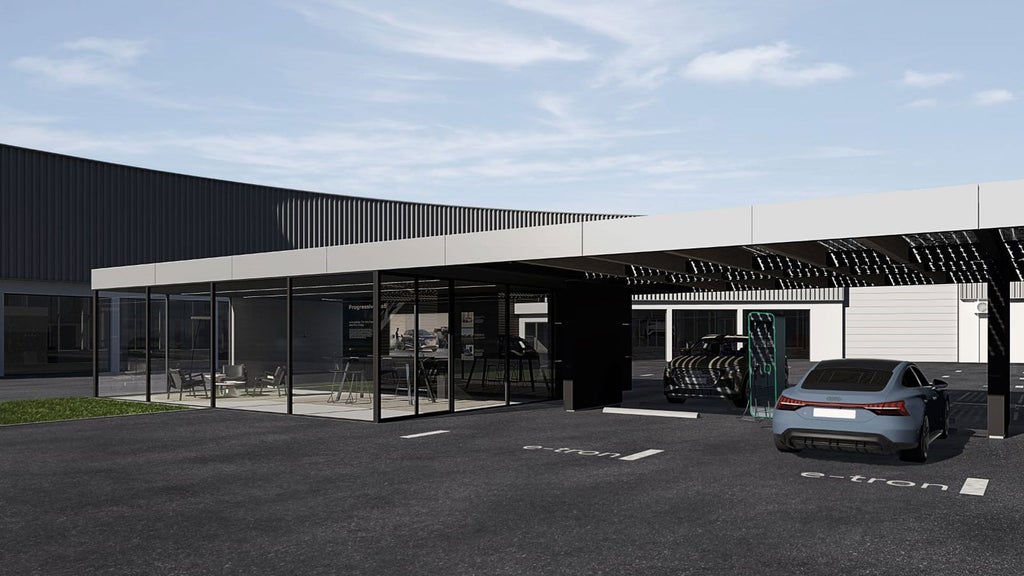 Two electric cars are parked under a solar roof charging station next to a modern, glazed building with seating.
