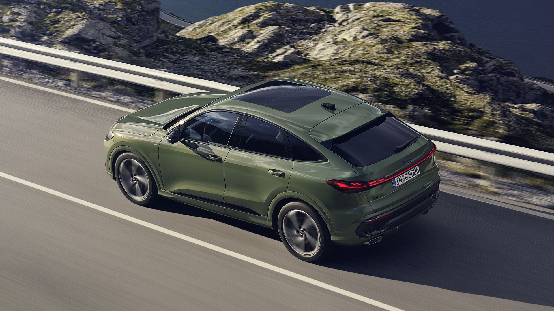 Der Q5 Sportback im schrägen Seitenprofil von oben betrachtet. Das Fahrzeug fährt auf einer Gebirgsstraße.