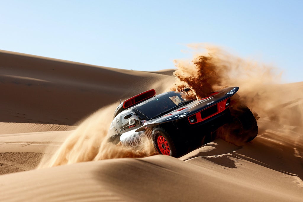 En Audi RS Q e-tron flyger över en sanddyn.