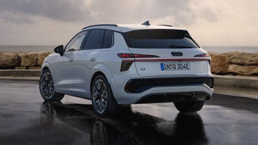Ein weisser Q3 SUV e-hybrid fährt auf nasser Strasse entlang der Küste.