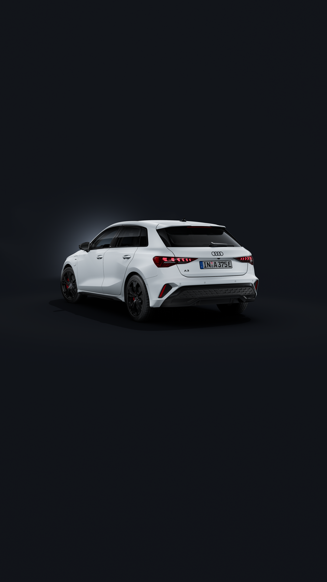 The Audi A3 Sportback e-hybrid, viewed from the rear at an angle against a dark background.