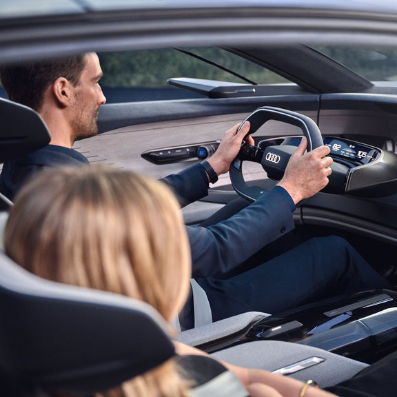 En man som sitter i cockpit körandes en Audi grandsphere concept, i passagerarsätet sitter en kvinna