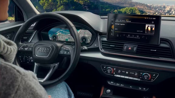 Interior view of an Audi vehicle focusing on the steering wheel and infotainment system.